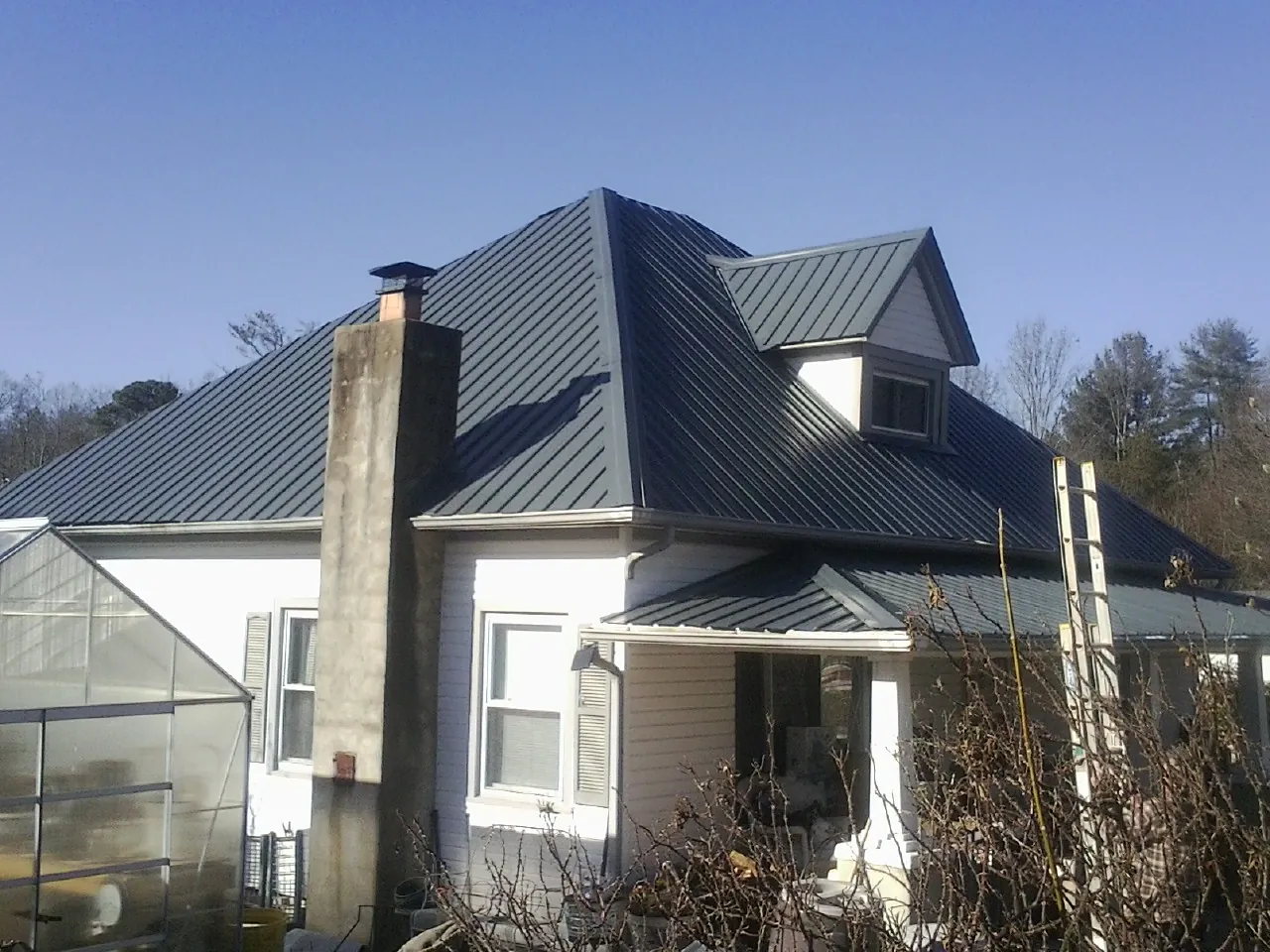 Dark blue standing seam metal roof on a white farmhouse with dormer — Slate & Tile Roof Repair by Roofing Brothers in Addyston