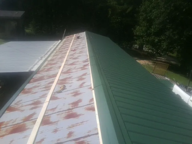Old rusted panels beside newly installed green metal roofing — Wind Damage Roof Repair by Roofing Brothers in Addyston