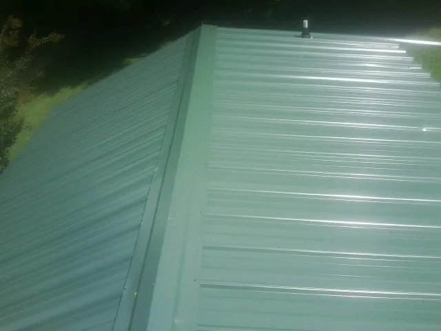 New green metal panels meeting at the ridge of a roof — Flat Roof Repair work by our crew in Addyston