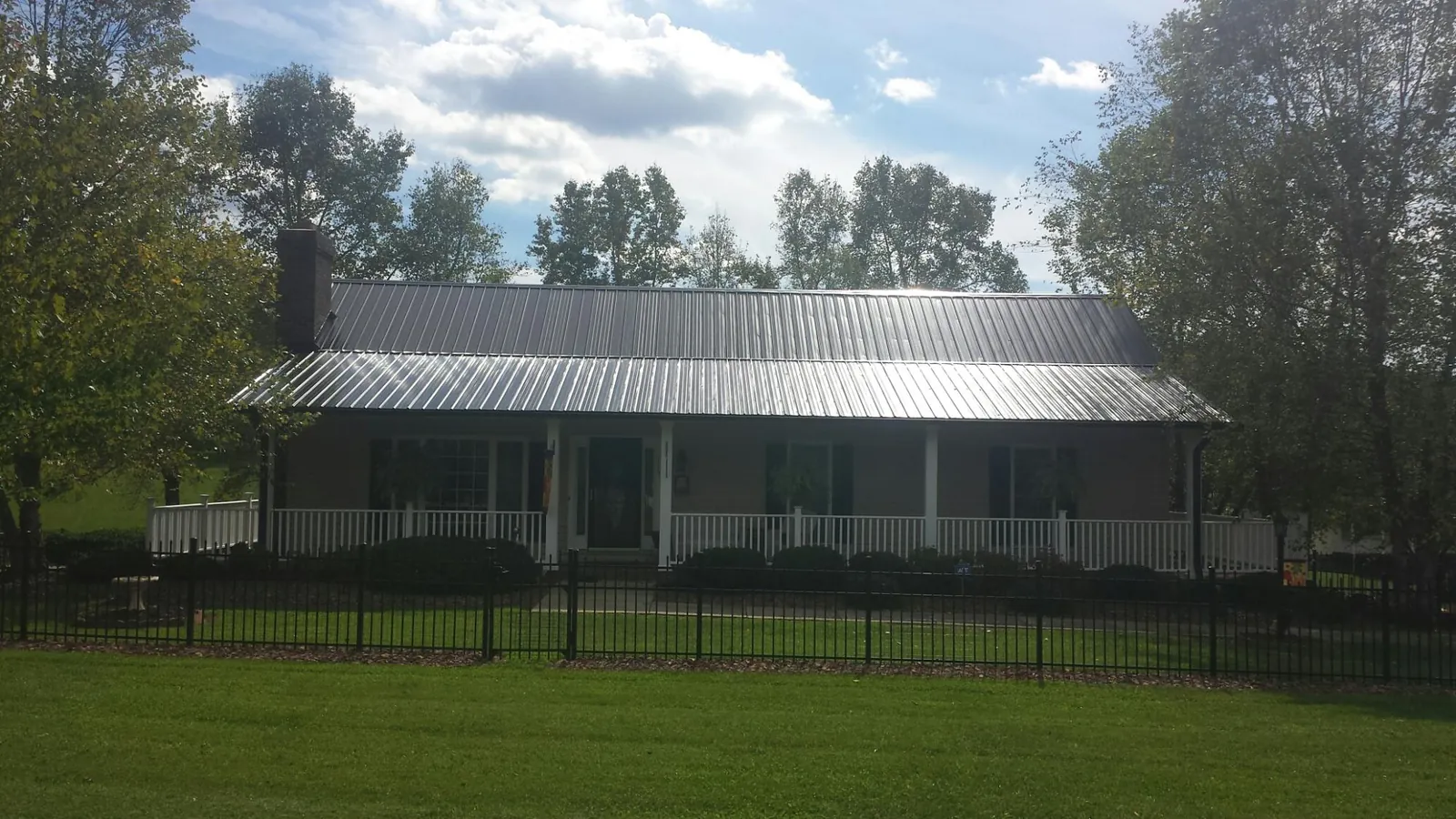 Gray metal roof on a brick ranch with a full width front porch — Gutter Guard Installation work by our crew in Addyston