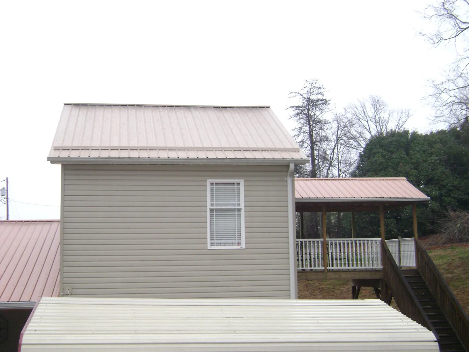 Tan metal roofs on a two story addition and attached porch, from a Roof Replacement job in Addyston