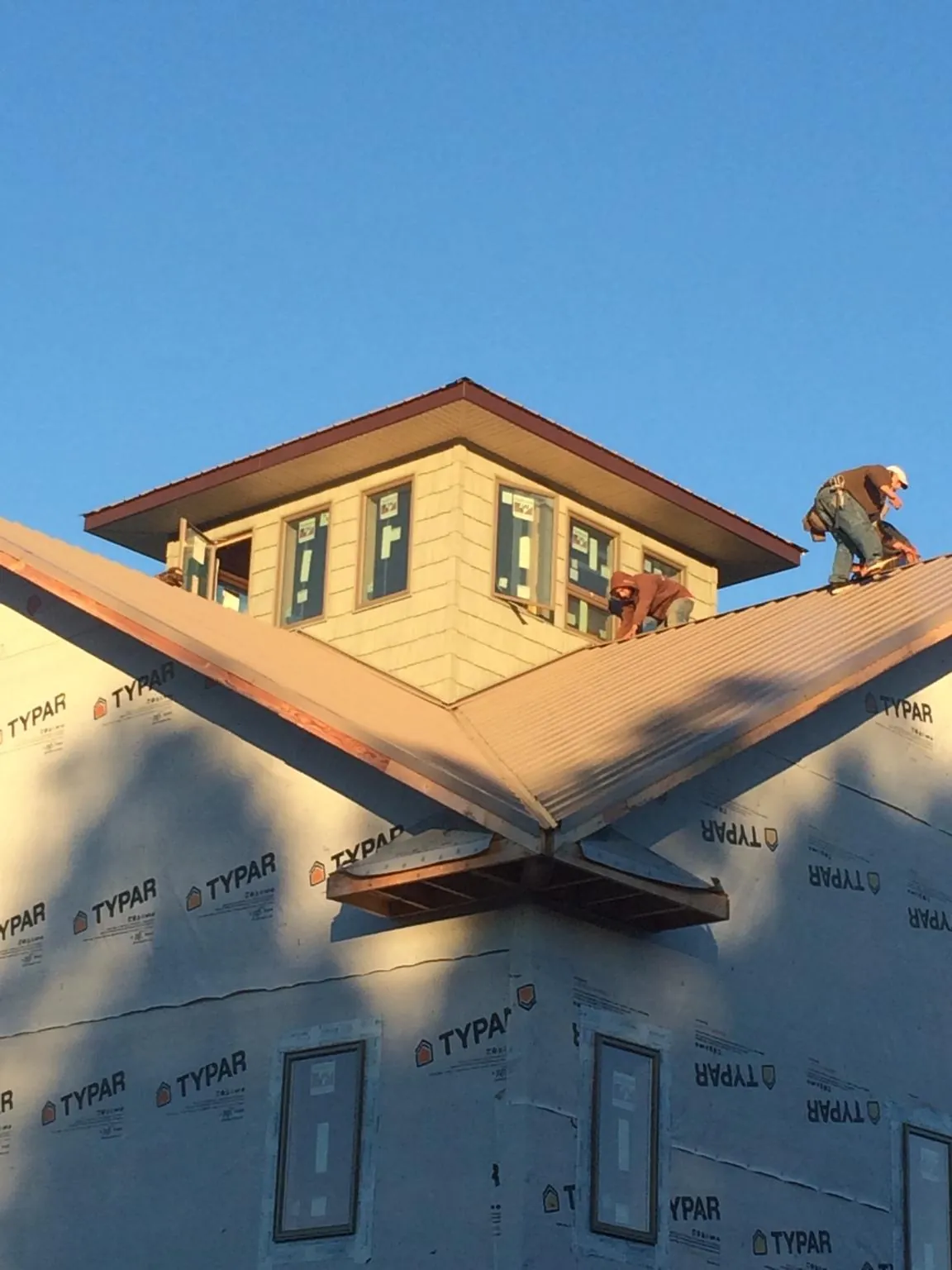 Roofers working around a rooftop cupola on a new metal roof at sunset — Roof Waterproofing in Addyston by Roofing Brothers